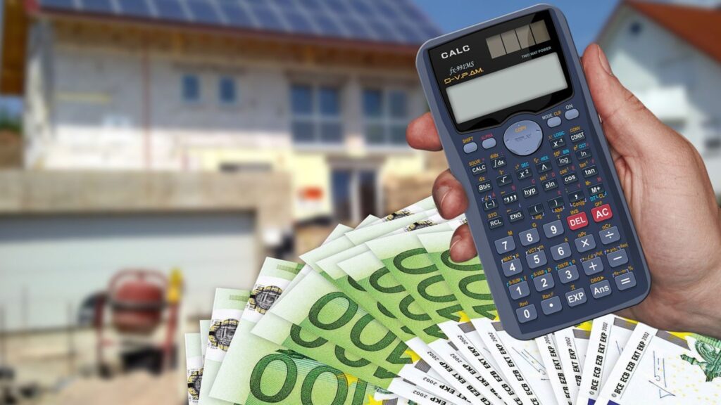 מחשבון פיננסי ושטרות כסף מול בית בתהליך בנייה – מסמל חישוב עלויות נכס נדל"ן ופוטנציאל השבחה
